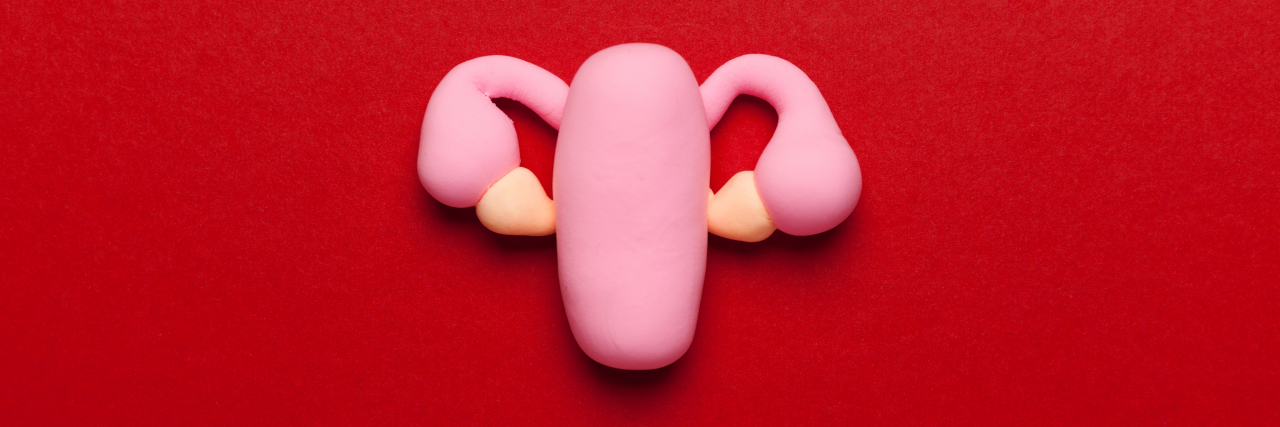 Uterus sculpture on red background.