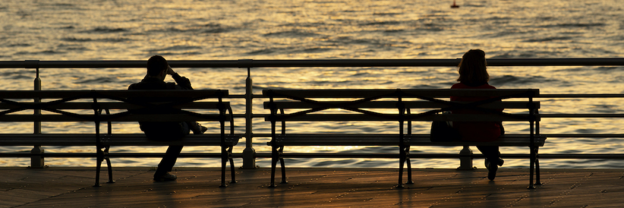 The Power of Stories, Listening to One Another and Human Connection Silhouette of two people sitting on park benches in front of river and skyline at sunset