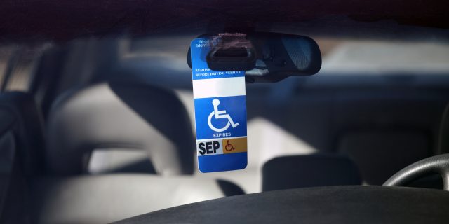 6 Reasons Not to Feel Guilty About Using a Disability Parking Placard Disabled parking permit hanging in the window of a car.