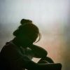 Silhouette of asian woman sitting in window with head facing down