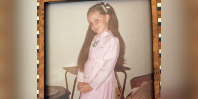 Photo frame of the author as a young girl in a pink dress smiling