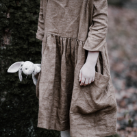 photo of a young girl holding a rabbit plush by her side, wearing a discoloured dress