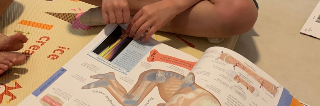 Why School Reports Saying Autistic Kids 'Rely On' Supports Are Ableist Autistic child and sibling reading a book.