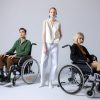 Two wheelchair users and a person with a mobility disability standing between them.