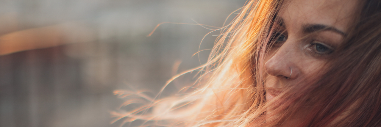 It's Time to Stop Referring to Health Issues as Shameful Woman with red hair holding her knees.