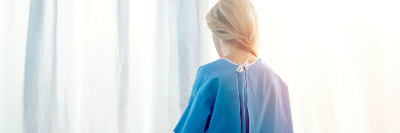 Exploring Vulnerability and Humanity at Midlife With Chronic Illness View of woman from the back wearing a hospital gown in front of a curtain