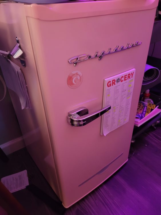 A pink frigidaire mini fridge with a calendar on it