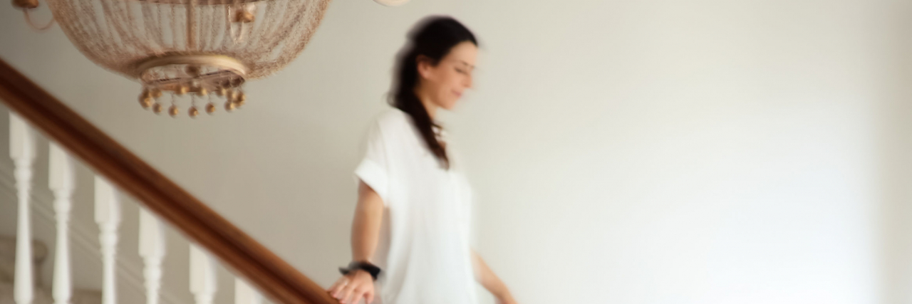 How Chronic Migraine Impacts My Social Life Natalie walking slowly downstairs.
