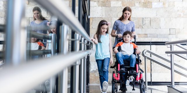 To the Family and Friends Who Offer Support as I Parent Kids With Disabilities Mother pushing son in wheelchair as daughter walks beside them.