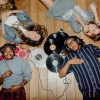 Group of young friends listening to music with vinyls scattered about