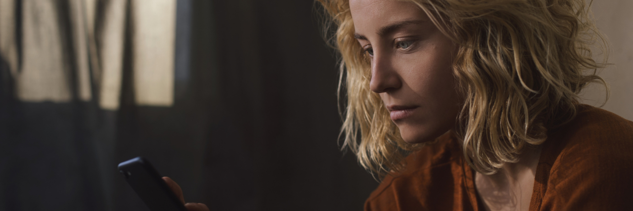 The Disability Benefits Process Is Making My Mental Health Worse photo of yougn woman with her phone looking upset