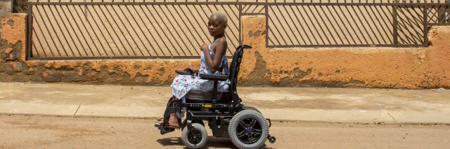 African woman using power wheelchair.