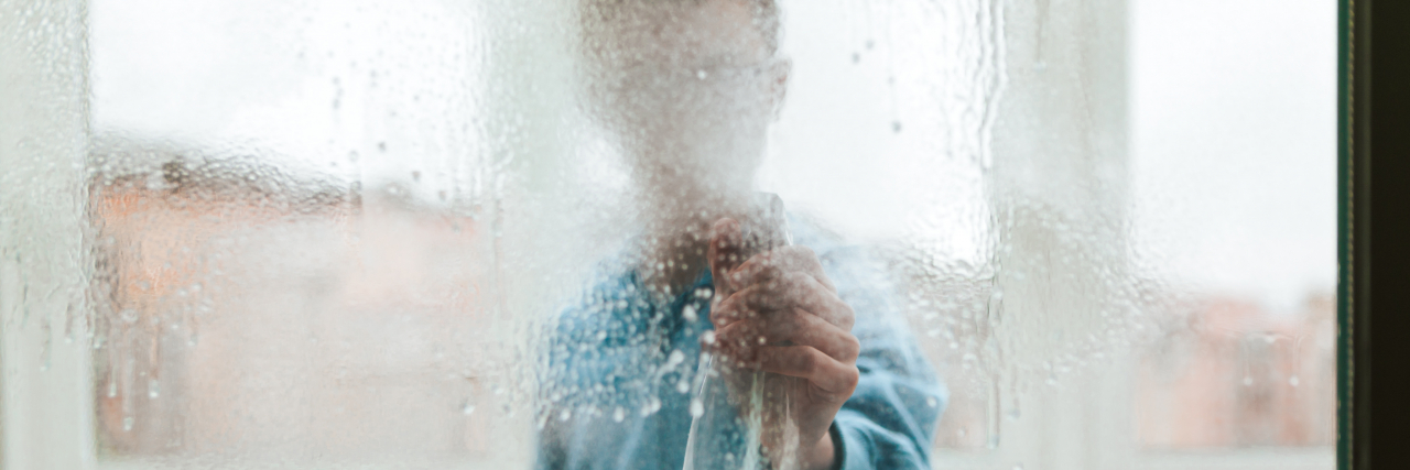 Portrait of a Window Cleaner Looking Through and Cleaning a Window