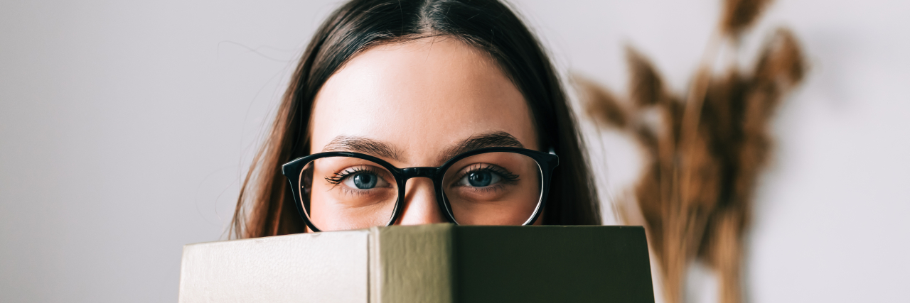 Why Does a Book About My Illness Assume I'm Not Reading It? Woman looking over the top of a book.