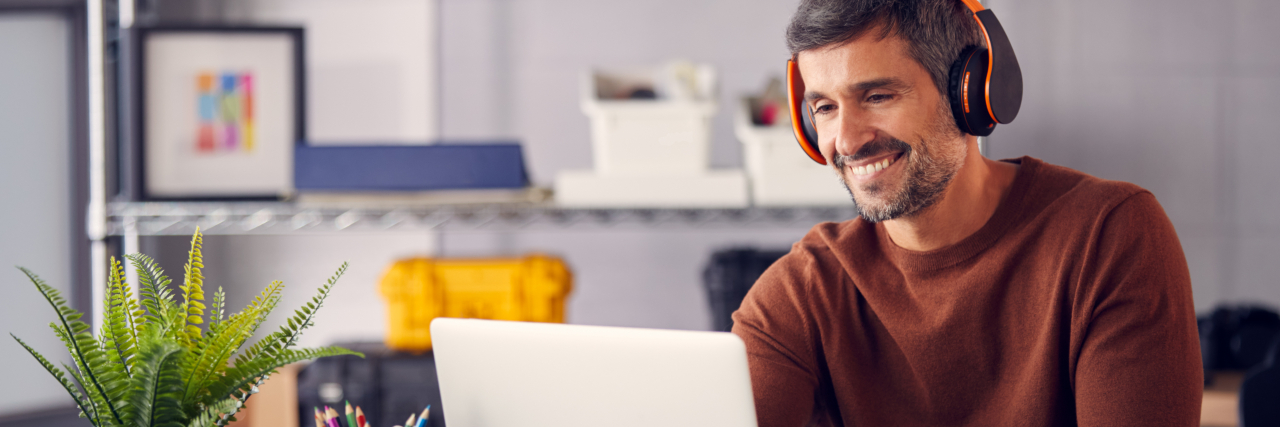 When It Comes to Neurodiversity, Awareness Isn't Enough Man wearing headphones working on laptop.