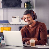 Man wearing headphones working on laptop.