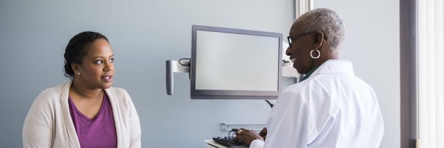 Black doctor speaking with Black female patient