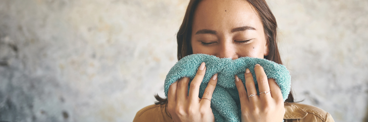photo of a young woman smelling a towel