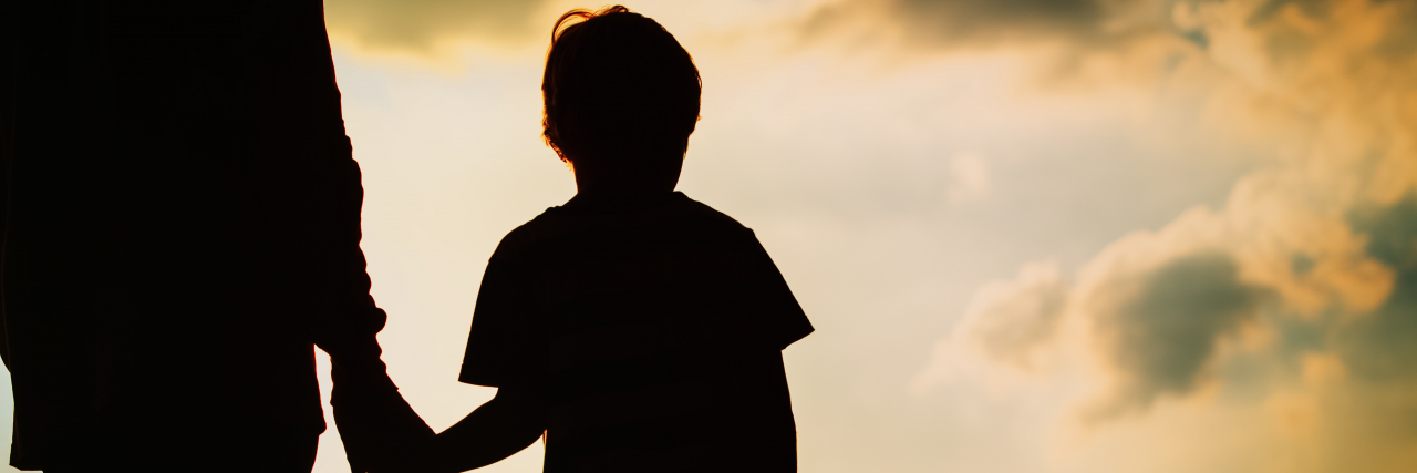 How Families Can Support a Non-Binary Child Parent and child holding hands at sunset.