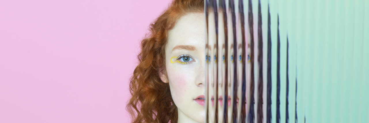 7 Reasons You Haven't Heard From a Friend With Mental Illness Young woman with curly red hair staring into the camera, half her face being split through glass