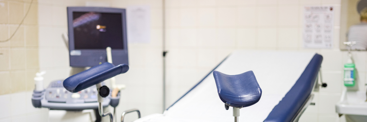 How Gynecologists Can Support Sexual Abuse Survivors Navy blue gynecological chair with ultrasound monitor.