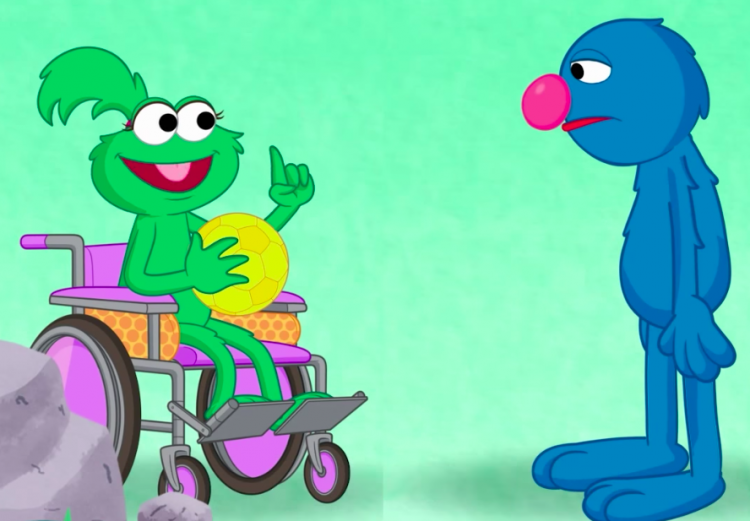 Ameera Muppet in her wheelchair, holding a ball and speaking with Grover