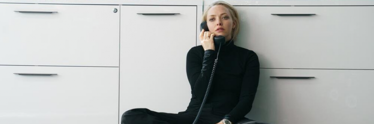 How Theranos Negatively Impacted People With Health Conditions Amanda Seyfried in a black turtleneck sitting against a desk making a phone call