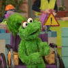 Muppet Ameera in her wheelchair speaking with another muppet