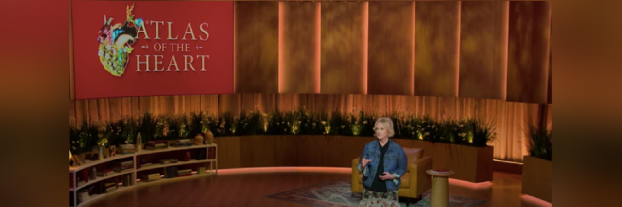 Brené Brown's New Docuseries Is the Emotional Education We All Need Brene Brown on stage with "Atlas of the Heart" text and image on screen behind her