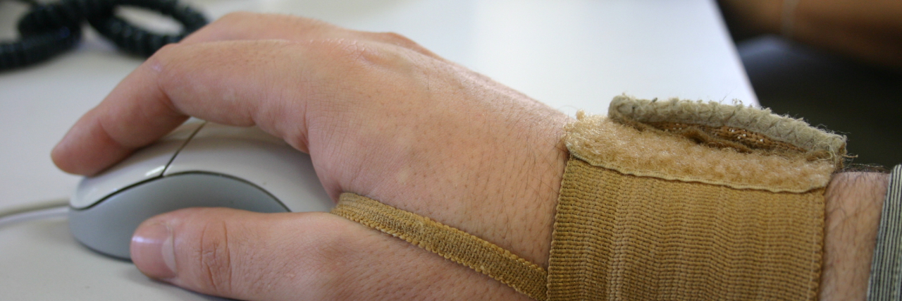How My Disabilities Are Affecting Me as a Writer Woman's hand using mouse. She is wearing a wrist brace.