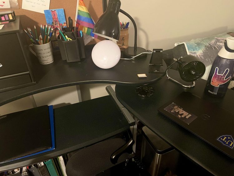 A desk with a brita water bottle, sensory objects, a candle, a therapy light, and organizers.