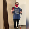 Korrine standing up, taking a selfie in a stand up mirror. Her dark brown curly hair is tied back in a bun. She's wearing glasses, hearing aids, and a red mask. She's holding her white cane in one hand and her phone in the other. She's wearing a navy blue shirt that says DISABILITY is not a bad word, black leggings, and dark gray converse shoes.