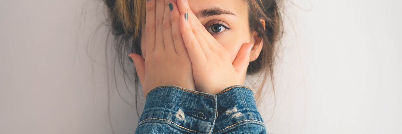 photo of a young woman partially covering her face with her hands