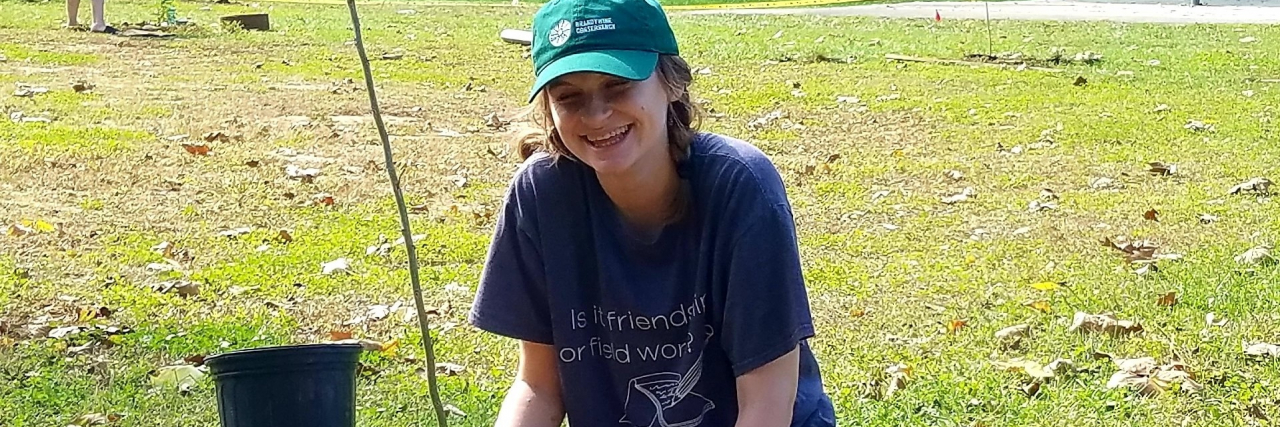 How Climate Justice, Climate Change, and Health Care Are All Connected photo of the author, Mighty editor Skye Gailing, planting a tree and smiling