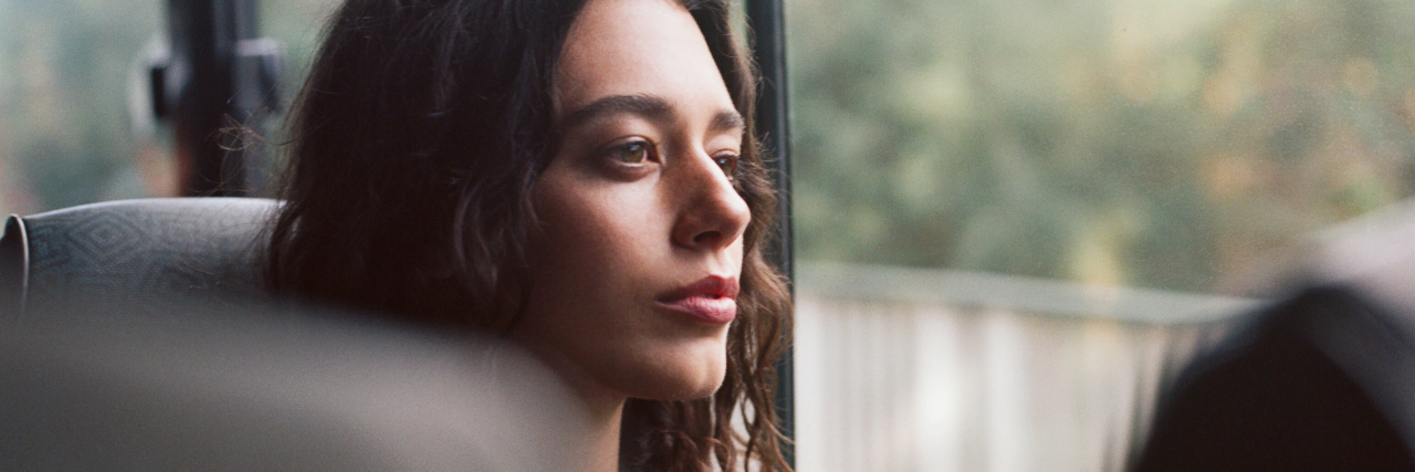Don't Compare What People With Disabilities Can Do A woman with curly brown hair looks out the window of a bus.