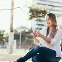 Woman sitting outside looking at her phone