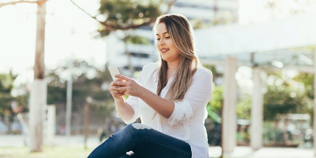 Woman sitting outside looking at her phone