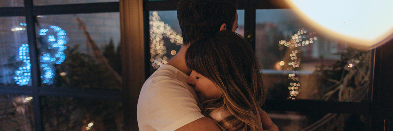 Preparing My Husband and Myself for the Return of My Mania Couple embracing in their home with lights around them