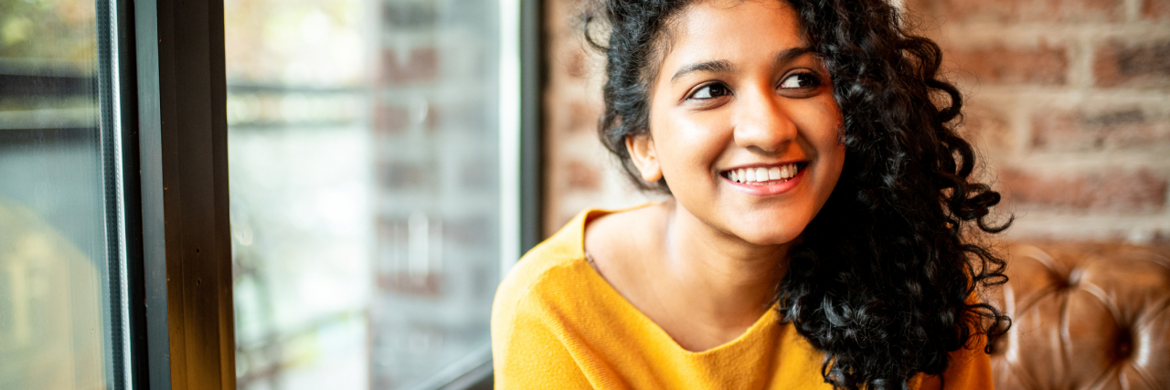 Positive Reinforcement at Work Has Actually Improved My Depression photo of a young person holding a phone and smiling at unseen person