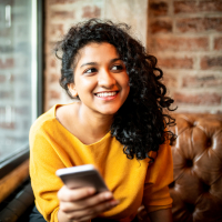 photo of a young person holding a phone and smiling at unseen person