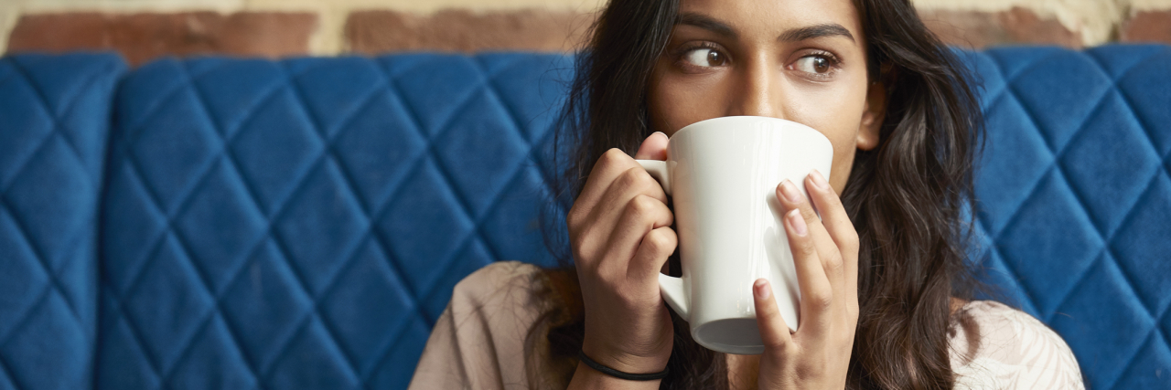 photo of a young person on a blue couch with a large mug partially hiding face