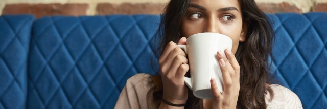 photo of a young person on a blue couch with a large mug partially hiding face