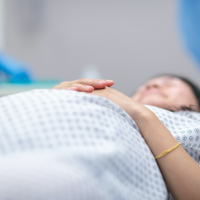 Pregnant woman wearing hospital gown and laying on operating table in preparation for surgery