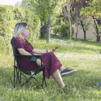 two women sitting outdoors with home made face masks.