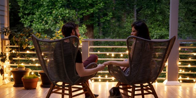 What Men Should Be Asking Their Female Partners About Their Reproductive Health A couple sit in chairs and hold hands on a home patio.