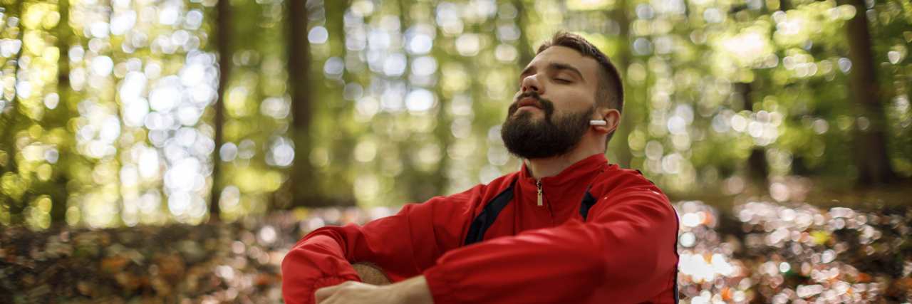 Man listening to music in a forest.