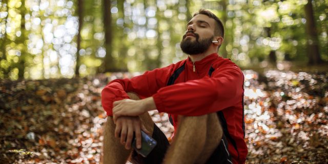 Man listening to music in a forest.