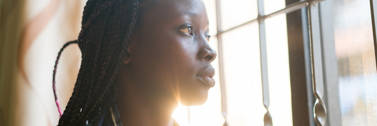 Why We Can't Make Assumptions About People With Our Health Condition Women looking through window contemplating and thinking at home