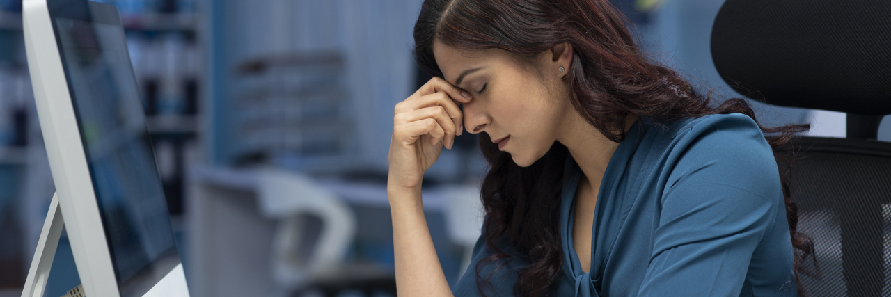 Hacks to Help You Get Through the Workday When You Have Anxiety photo of a woman looking stressed or tired in an office