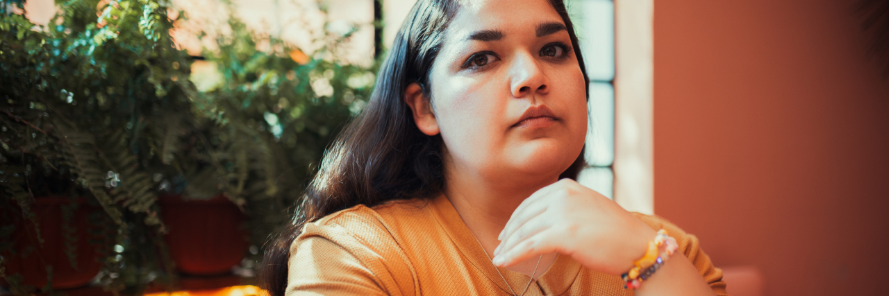 Amber Heard Trial: Borderline Personality Disorder Stigma Is Dangerous photo of a woman sitting at a table in sunlight looking serious into camera